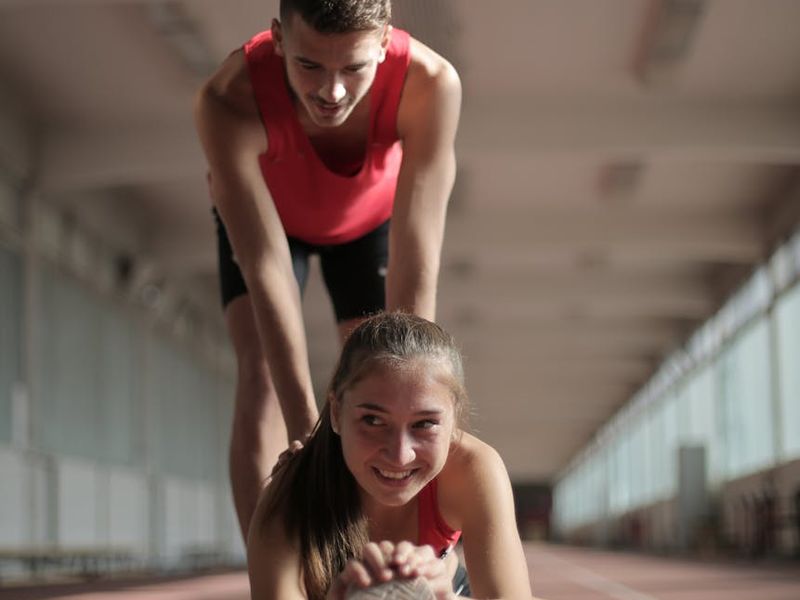 A man in mid-motion during a dynamic stretching exercise in a minimalist gym.