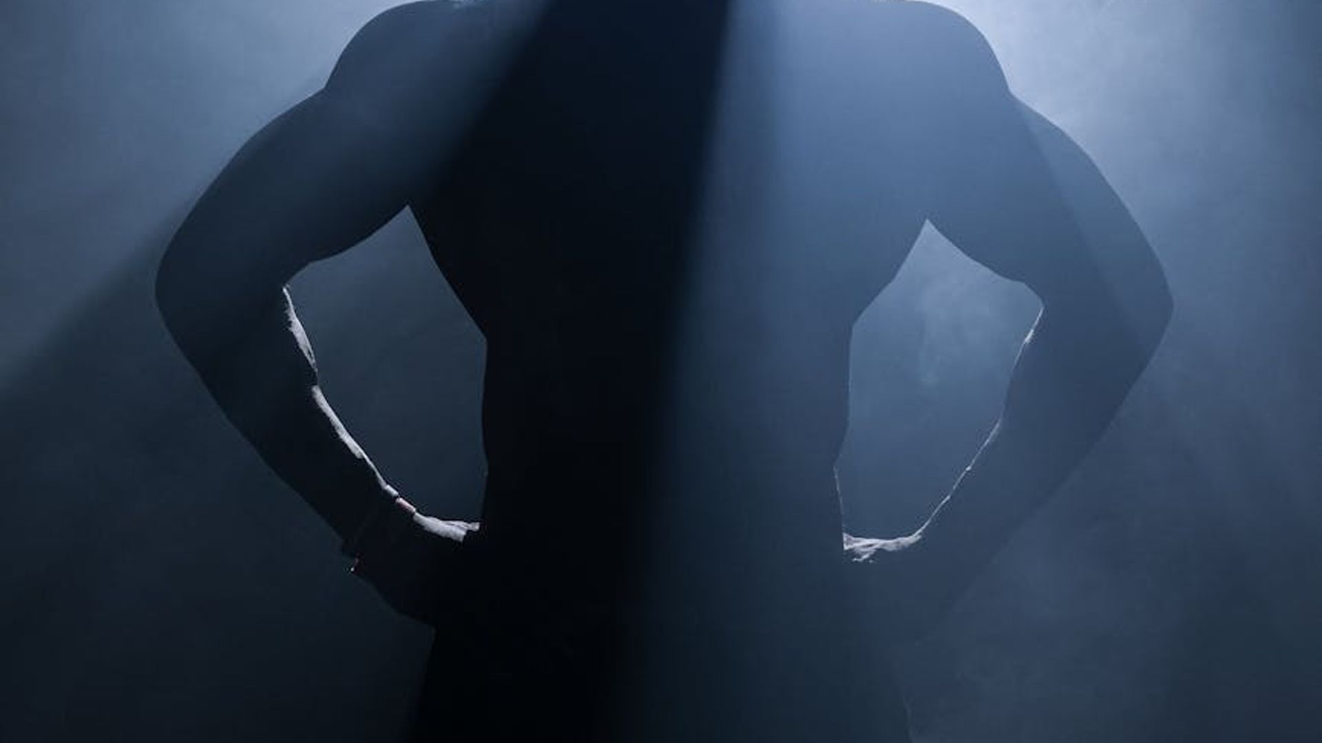 Silhouette of a man performing a strength exercise in a dark, atmospheric setting.